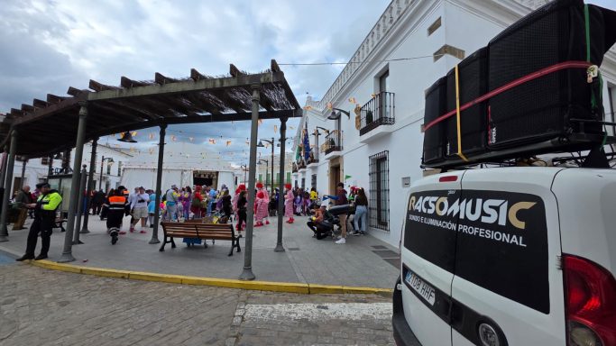 Festejo al aire libre con decoraciones, música y personas en un ambiente festivo.