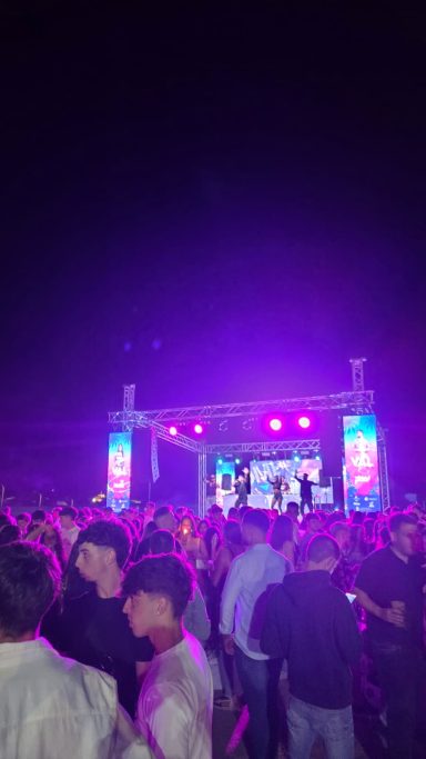 Multitud de personas disfrutando de un concierto al aire libre con luces brillantes.