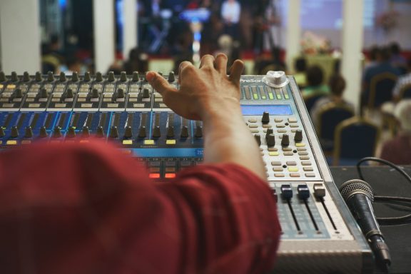 Persona ajustando los controles de una mesa de mezclas en un evento.
