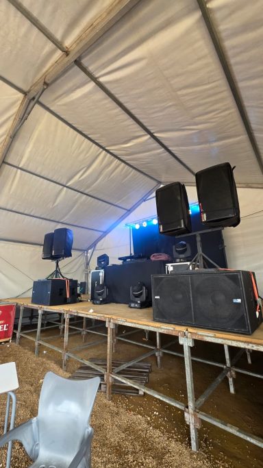 Un escenario con altavoces y luces en una carpa de evento.