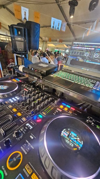 Mesa de DJ con luces coloridas y equipo de música en un ambiente festivo.